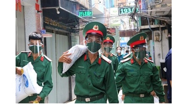 Soldats portant des sacs de riz pour faire don aux démunis de Hô Chi Minh-Ville, le 23 août. Photo : VNA.