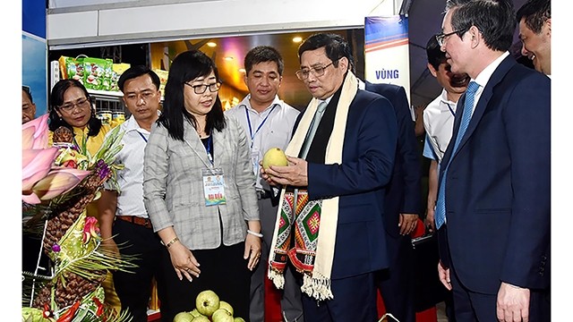 Le Premier ministre Pham Minh Chinh en visite dans un stand lors festival des fruits et des produits OCOP. Photo : NDEL.